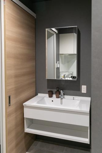 a bathroom with a white sink and a mirror at Shinosaka private house for 16ppl in Osaka