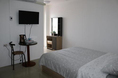 1 dormitorio con cama, mesa y TV en Cafe Nana Hotel en Nong Prue