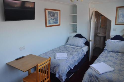 a room with two beds and a table and a tv at Avoncot Guest House in Stratford-upon-Avon