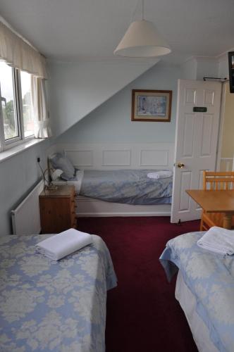 a hotel room with two beds and a table and a bed at Avoncot Guest House in Stratford-upon-Avon