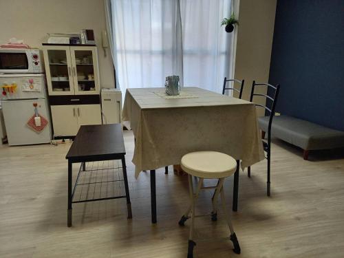 a kitchen with a table and two chairs and a refrigerator at FukuokaKoryou GuestHouse in Fukuoka