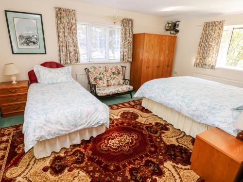 a bedroom with two beds and a chair and a rug at Otter Cottage in Newport