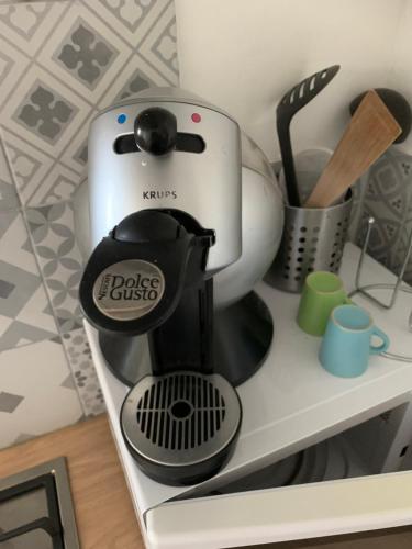 une cafetière noire et blanche assise sur une étagère dans l'établissement appartement dans maison basque, à Mouguerre