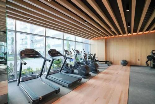 a gym with a row of cardio machines in a room with windows at Cozy studio, amazing amenities in Dubai