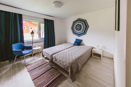 a bedroom with a bed and a blue chair and a window at YH Lappeenranta in Lappeenranta