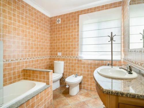 a bathroom with a tub and a toilet and a sink at Fonte do Forno Villas in Afife