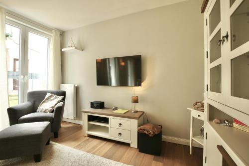 a living room with a chair and a tv on the wall at Ferienwohnung Strandperle im Haus Anna in Wangerooge
