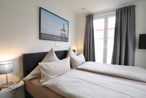 a bedroom with a bed with white sheets and a window at Ferienwohnung Strandperle im Haus Anna in Wangerooge