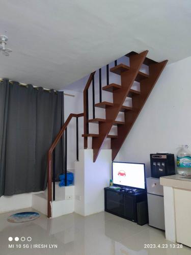 a living room with a staircase and a tv at iConnect Your Home Away From Home in Tagum
