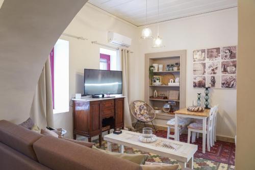 a living room with a couch and a tv at Traditional house of 1898 in the heart of old town of Nafplio in Nafplio