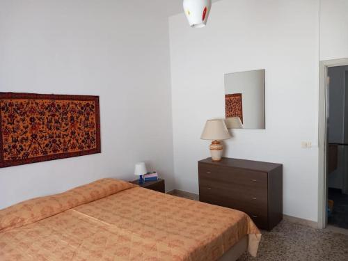 a bedroom with a bed and a dresser and a lamp at Ampio appartamento per 4/6 pers in Cesenatico