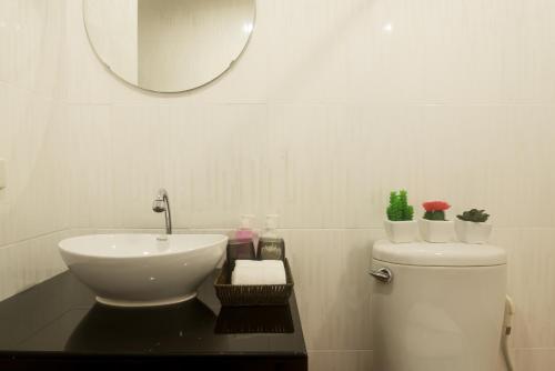 a bathroom with a sink and a toilet and a mirror at Green Leaf Hostel in Phuket Town