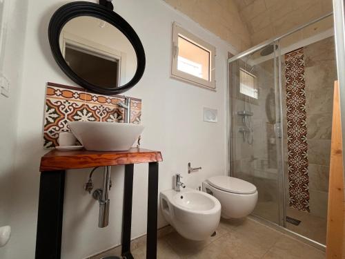 een badkamer met een wastafel, een toilet en een spiegel bij Trullo Al Guappo d'Oro in Ostuni