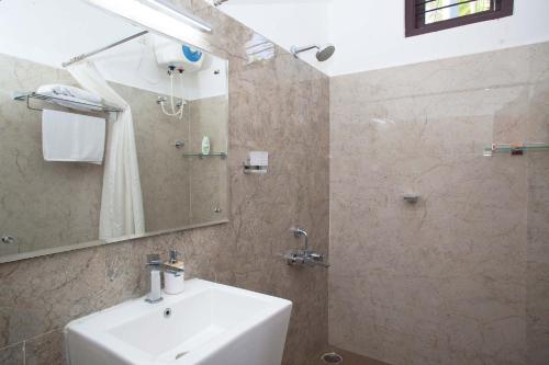 a bathroom with a sink and a mirror and a shower at StayVista at Ivory Hill Madikeri including breakfast 3 Bhk Villa in Madikeri