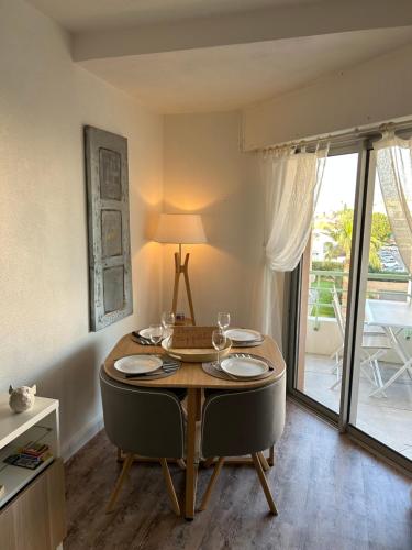una sala da pranzo con tavolo, sedie e finestra di Joli studio les pieds dans l'eau a Fréjus