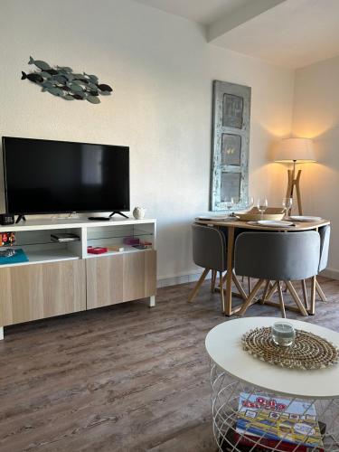 uma sala de estar com uma televisão de ecrã plano e uma mesa em Joli studio les pieds dans l'eau em Fréjus