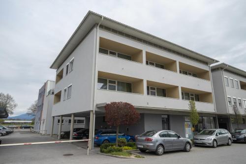 un edificio bianco con auto parcheggiate in un parcheggio di PM-PremiumAPART Strassgang a Graz