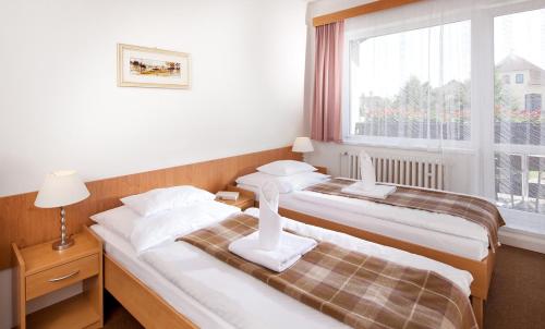 two beds in a room with a window at Penzion Hubert Františkovy Lázně in Františkovy Lázně