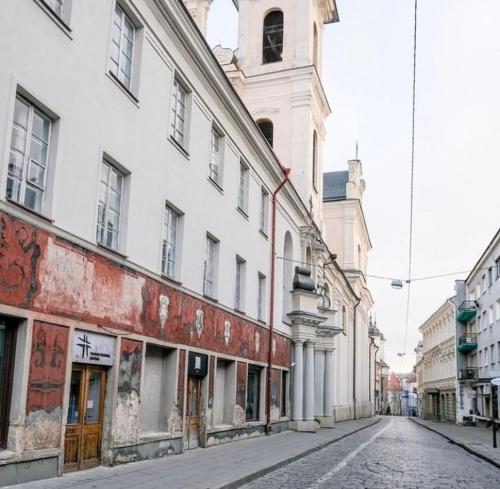 une rue urbaine vide avec un bâtiment et une tour de l'horloge dans l'établissement Rooms and Suites at Bookinn B&B, à Vilnius