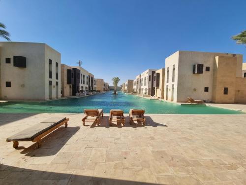 dos bancos en un patio con una piscina de agua en 1 Bedroom, Pool view and 2 balconies, Scarab Club en Hurghada