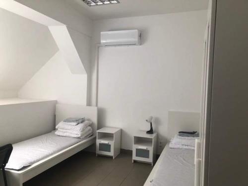 ブダペストにあるKonvoj szállóの白い部屋で、ベッド2台、窓が備わります。