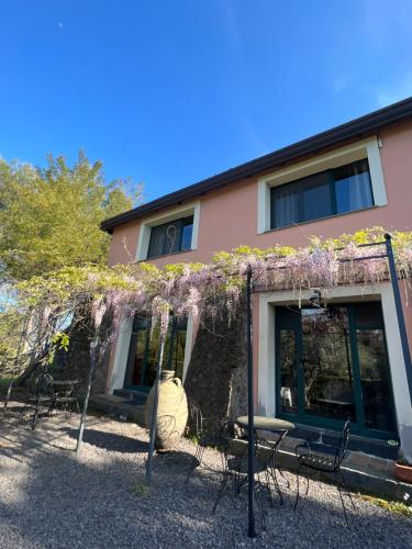 a building with a bunch of chairs and purple flowers at Bed and Breakfast Il Glicine in Piedimonte Etneo