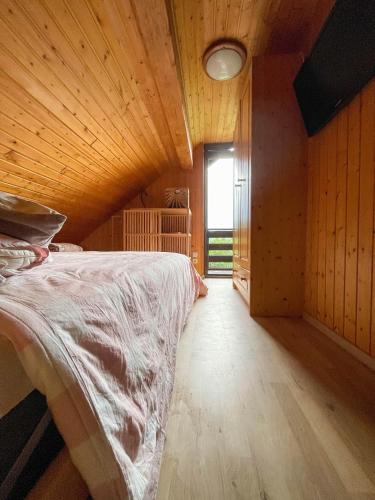 a bedroom with a bed with a wooden ceiling and a window at Dwarfs cabin overlooking Julian Alps near Bled in Jesenice