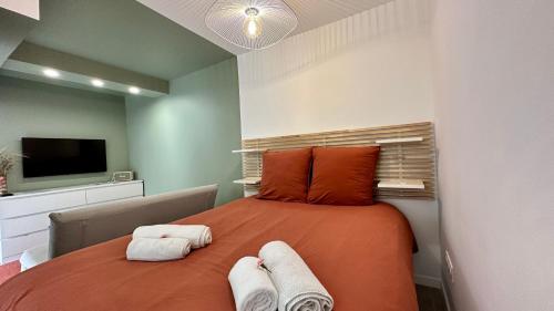 a bedroom with a large orange bed with towels on it at L'Indépendant in Nemours