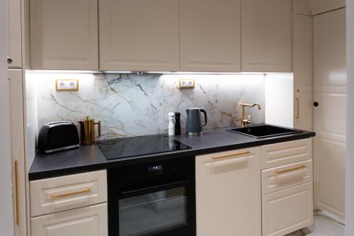 cocina con armarios blancos y encimera negra en Rome City Center Apartment, en Roma