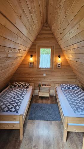 two beds in a log cabin with a window at Lepa Lopa resort in Stahovica