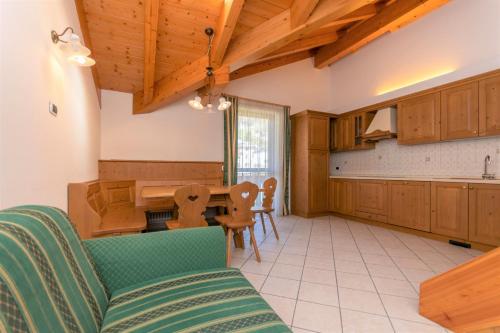 una cocina con armarios de madera, mesa y sillas en Appartamenti Villa Elisa, en Falcade