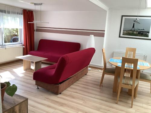 ein Wohnzimmer mit einem roten Sofa und einem Tisch in der Unterkunft Apartments In Cuxhaven-Döse in Cuxhaven