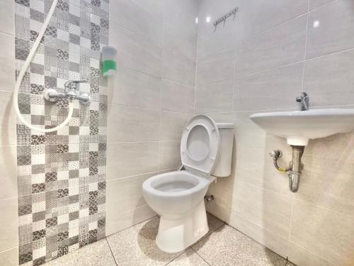 a bathroom with a toilet and a sink at Pringgondani Guesthouse Pandanaran Hills in Semarang