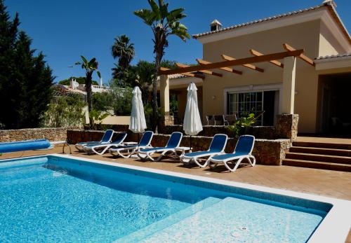 a villa with a swimming pool and lounge chairs at Casa Dos Cedros in Carvoeiro