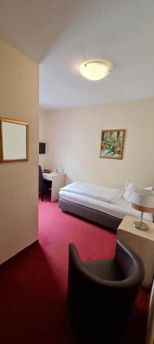 a hotel room with a bed and a chair at Hotel Am Sudenburger Hof in Magdeburg