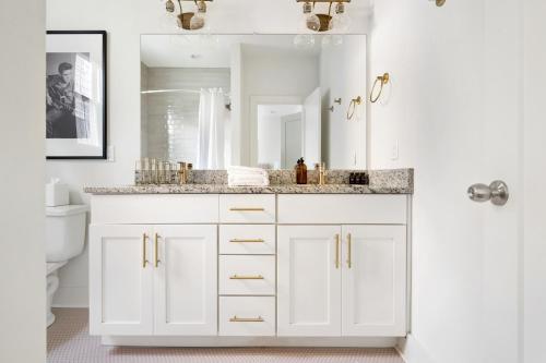 a white bathroom with a sink and a mirror at The Hart Suites by AvantStay in Nashville