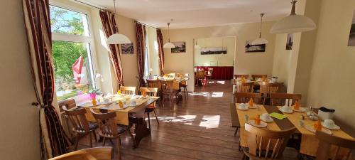 a restaurant with wooden tables and chairs and a window at Hotel Am Sudenburger Hof in Magdeburg