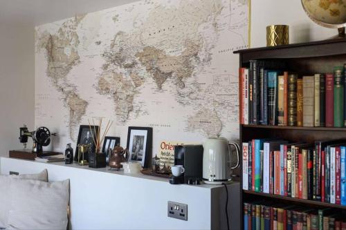 a map of the world on a wall with books at Luxurious cabin with desk & mini library in Parkstone