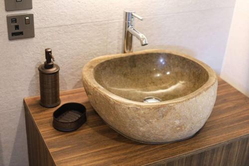 um lavatório de pedra num balcão de madeira com um dispensador de sabão em Luxurious cabin with desk & mini library em Parkstone