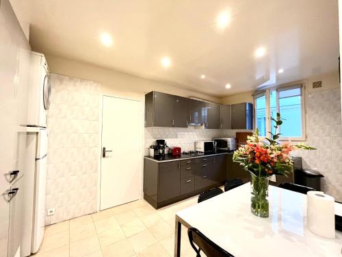 une cuisine avec une table avec un vase de fleurs dessus dans l'établissement Cosy appartment in the marais district, à Paris