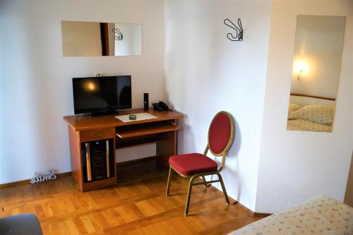 a room with a desk with a television and a chair at Kleine Hexe B&B Pension in Pirovac