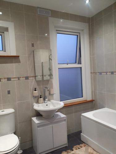 een badkamer met een wastafel, een toilet en een raam bij The Westcliff Room in Southend-on-Sea