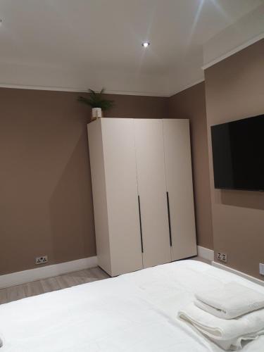 een slaapkamer met een witte kast en een televisie bij The Westcliff Room in Southend-on-Sea