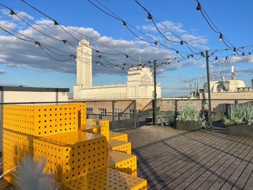 a rooftop deck with yellow benches and a building at Center stay Kaunas - Peledyne - Owl's nest apartments in Kaunas