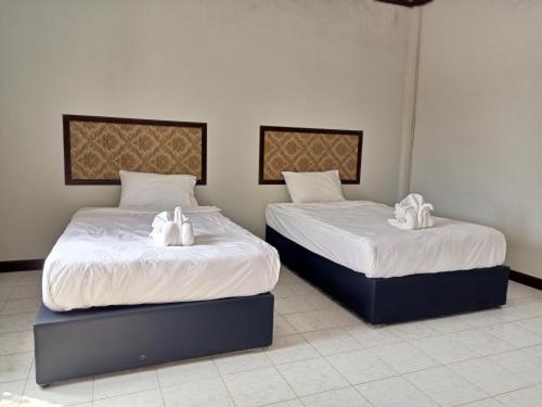 twee bedden in een kamer met witte handdoeken erop bij Meesouk Guesthouse 