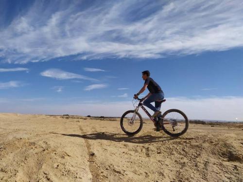 un hombre montando una bicicleta en el desierto en Eden Desert House- עדן במדבר, en Retamim