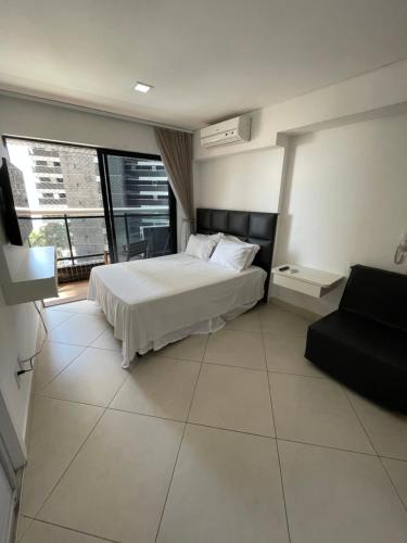 a bedroom with a white bed and a couch at Landscape Beira Mar Fortaleza in Fortaleza