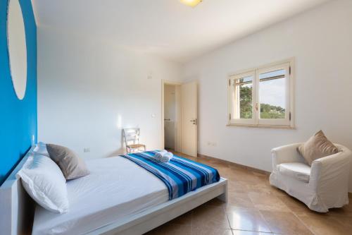 a white bedroom with a bed and a chair at VILLA BIANCA con piscina e vista mare in Gagliano del Capo