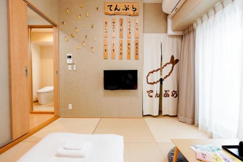 V の Boutique House في أوساكا: غرفة معيشة مع تلفزيون على الحائط
