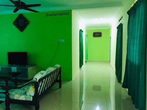 a green wall in a living room with a couch at Hijau Homestay in Sungai Besar